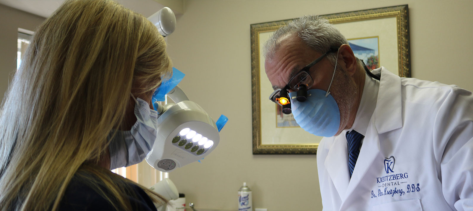 The image depicts a dental office setting, with a dentist and patient.
